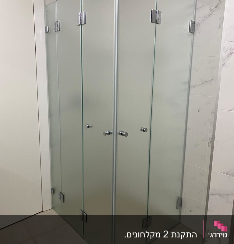 מקלחון זכוכית עם דלתות מתכת בחדר אמבטיה